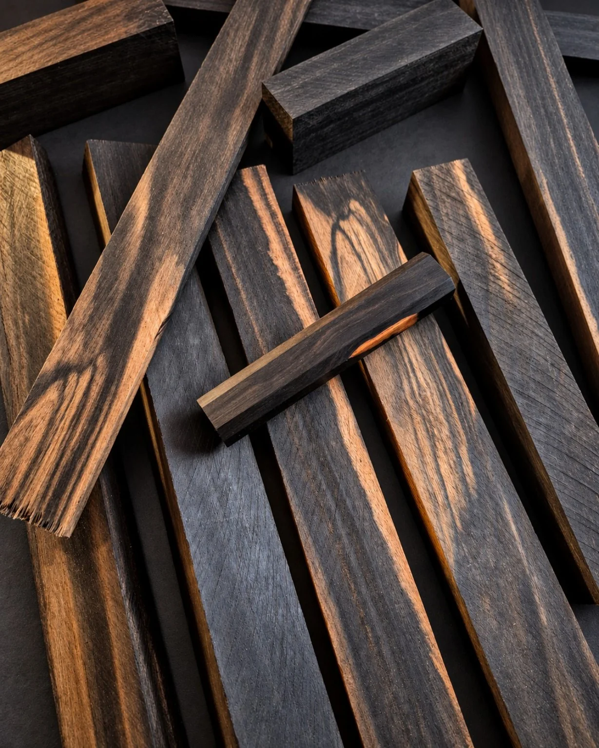 Close-up arrangement of dark ebony-like timber blanks, with rich contrasting brown figure