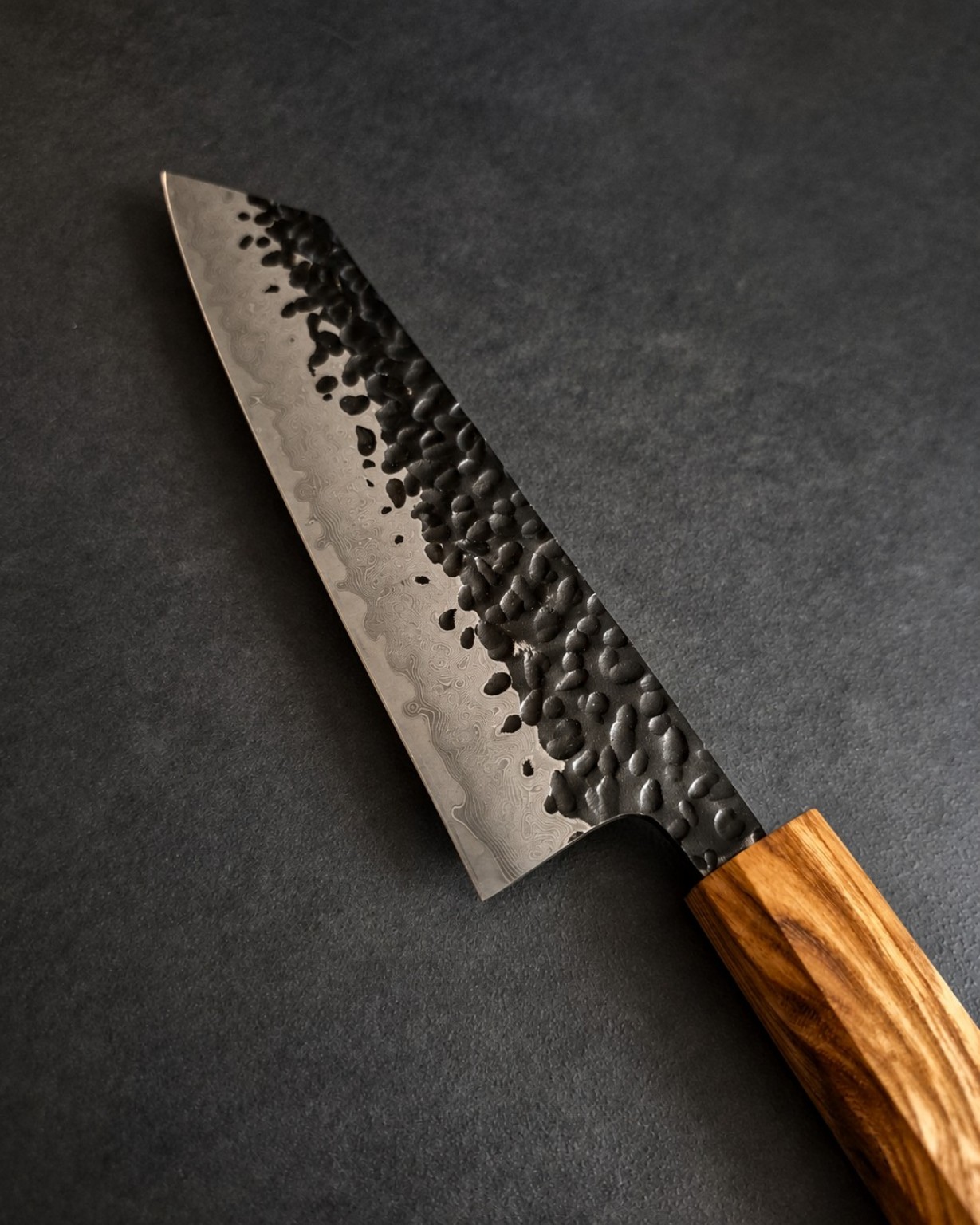 Close-up of Kiritsuke Bunka blade showing tsuchime hammering and the Damascus layered pattern