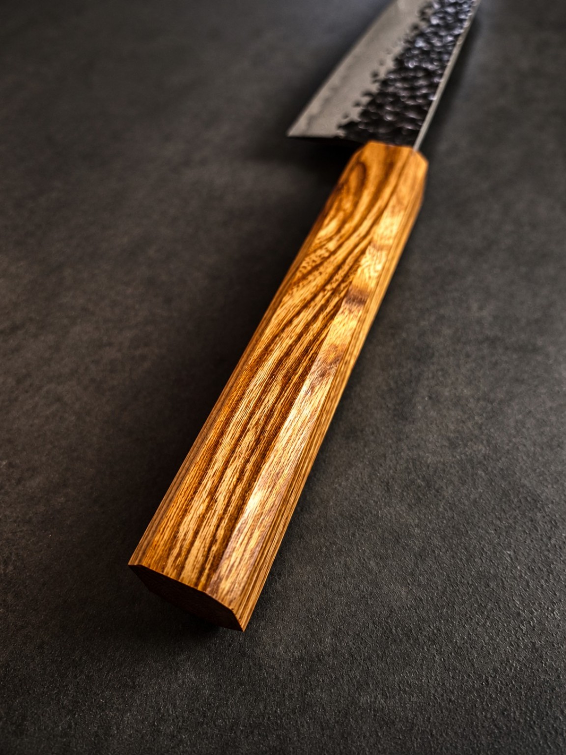 Angled view of the golden Goldregen handle, showing grain transitions along the wooden surface