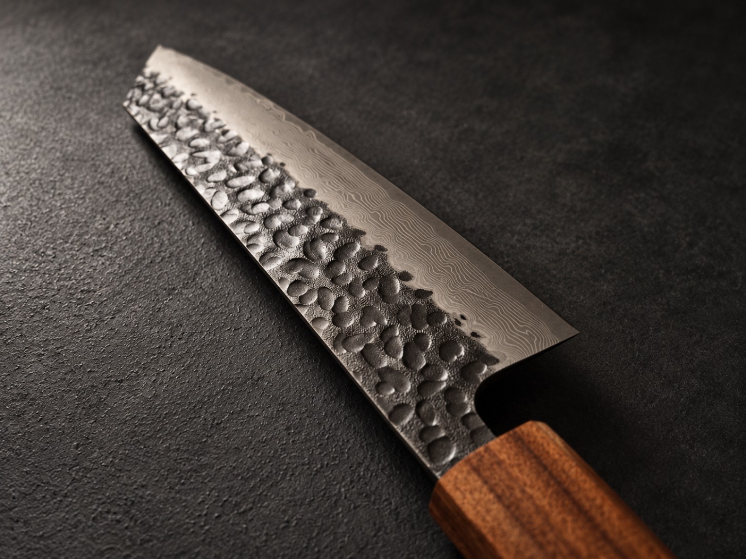 Close-up of the Kiritsuke Bunka blade, showing tsuchime hammered finish and layered Damascus steel pattern