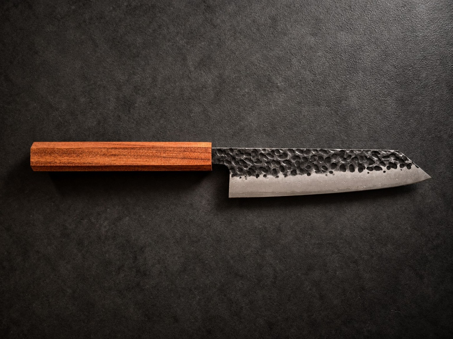 Complete 150 mm Kiritsuke Bunka kitchen knife with warm reddish-brown Mopane wood handle and hammered Damascus-pattern steel blade