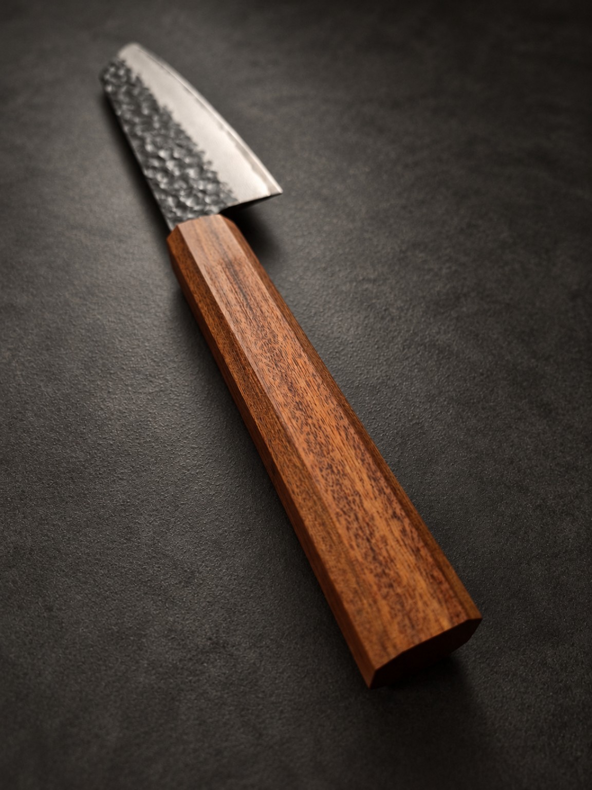 Perspective view of the reddish-brown Mopane wa-style handle, showing natural grain and the knife blade beyond