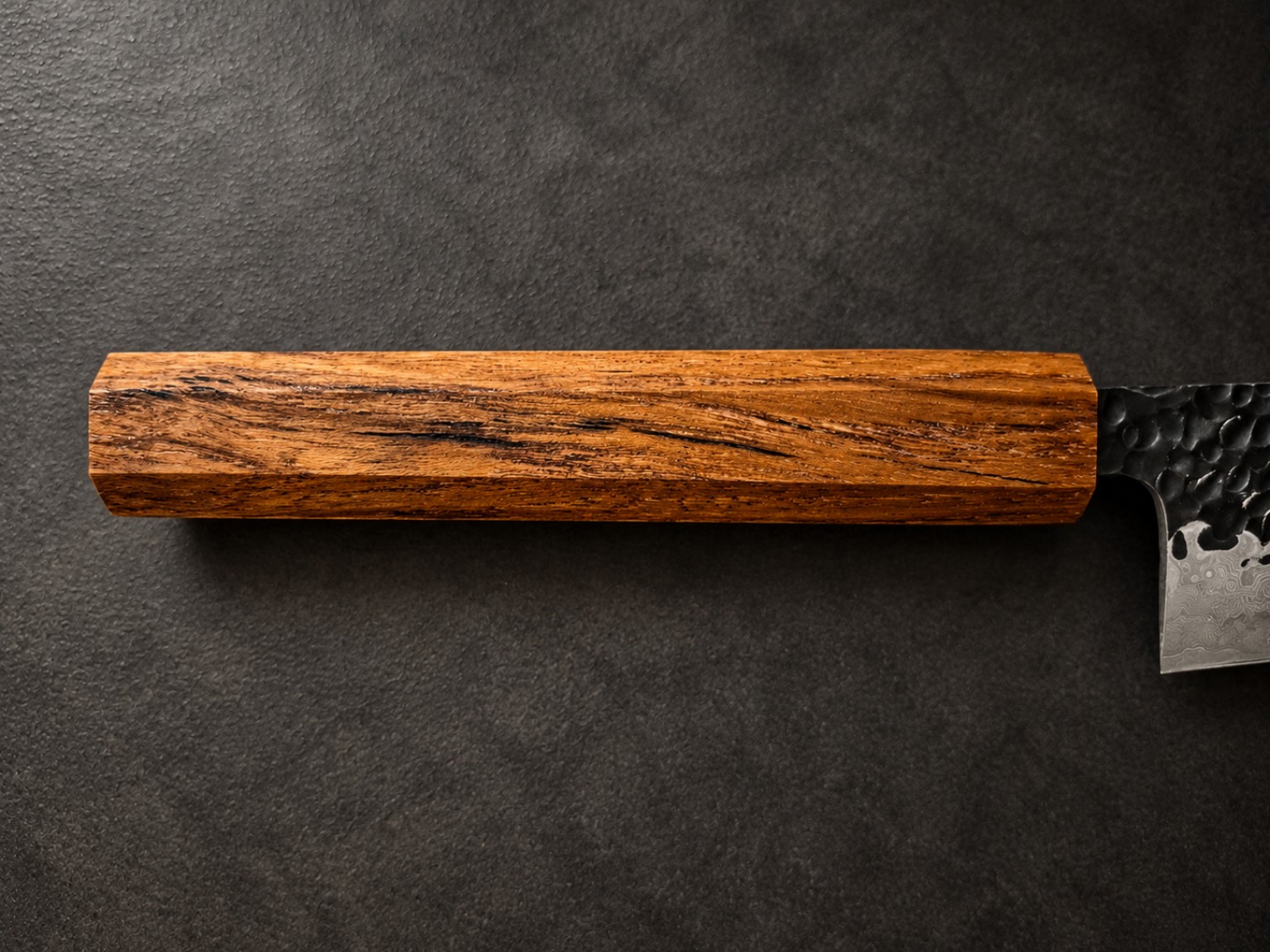 Horizontal close-up of golden-brown Teak handle, showing contrasting black natural streaks